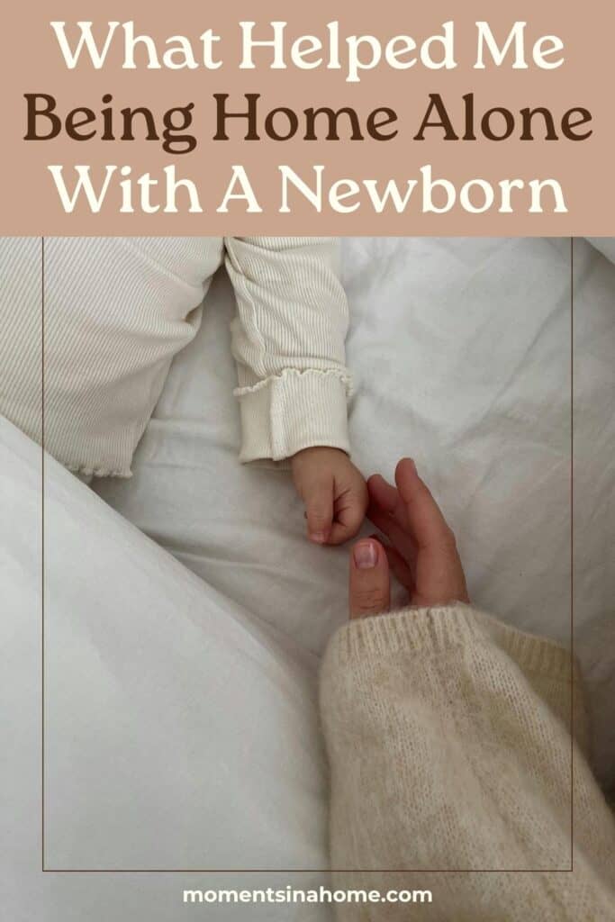 Mom home alone with a newborn reaching for newborns hand in the bed